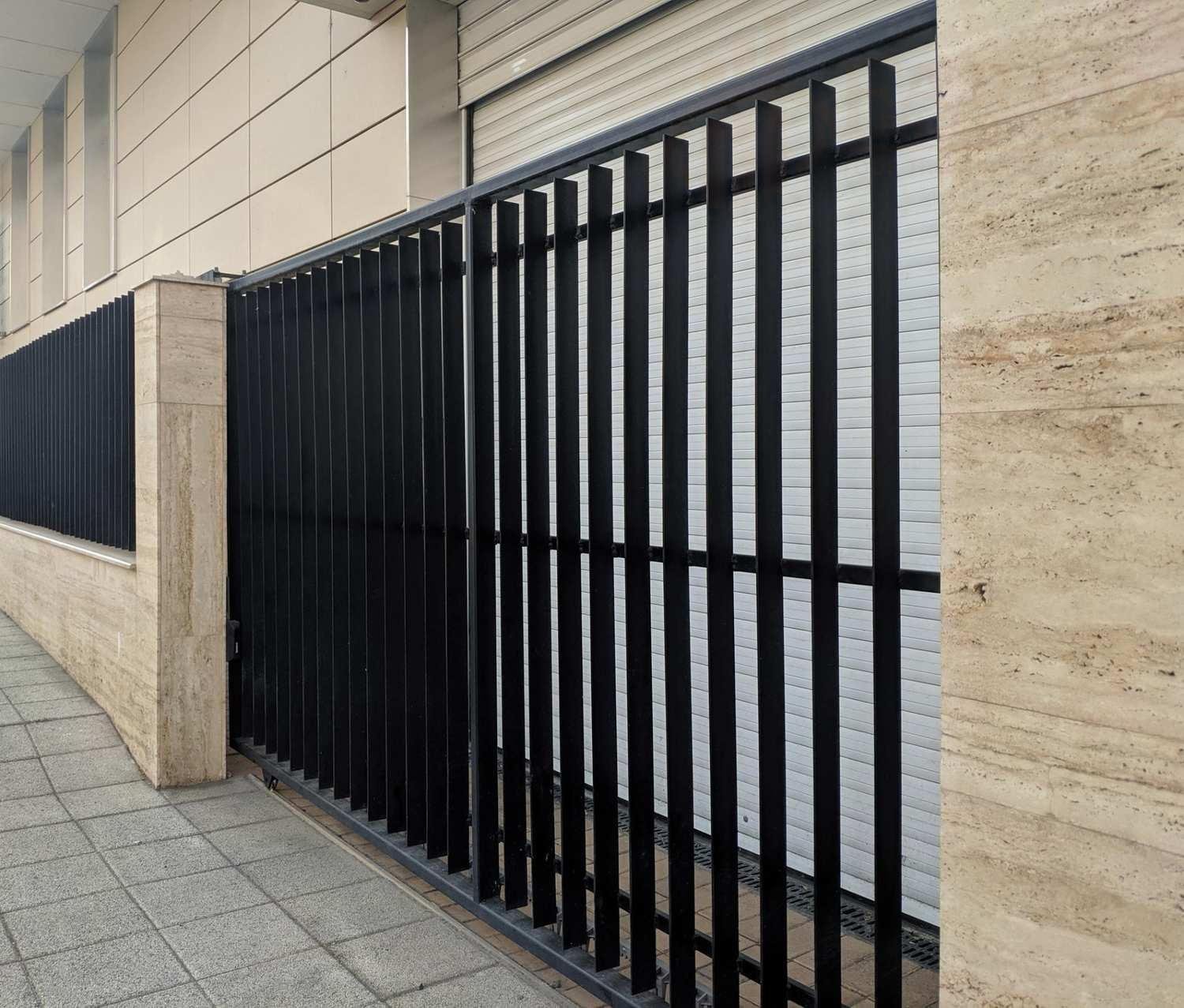 Modern, custom-designed black metal fence installed against a stone wall, showcasing bespoke fencing solutions in Fargo, ND.