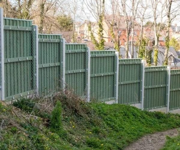 Green closeboard fence installation on a sloped yard with concrete posts and gravel boards in Fargo.